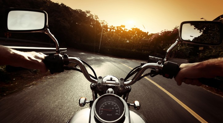 Driver riding motorcycle on an asphalt road through forest