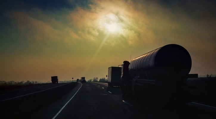 Gasoline tanker rides the highway in the evening sun rays