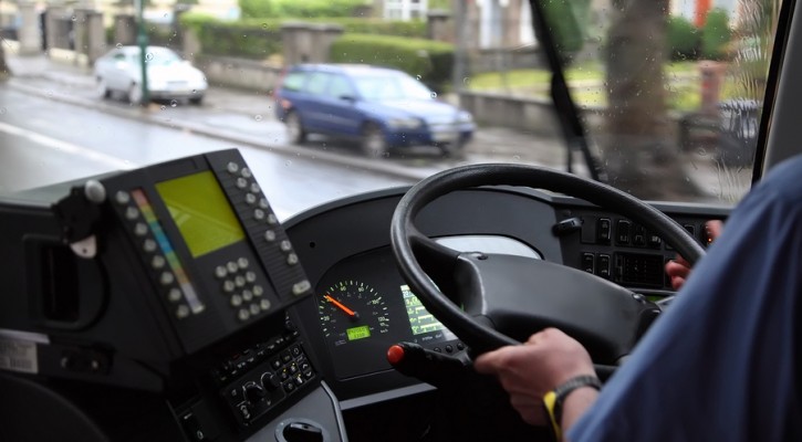 man in blue shirt riding in a bus on a wet road