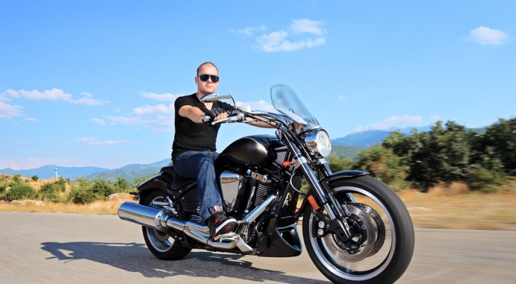 A young biker riding a customized motorcycle on an open road
